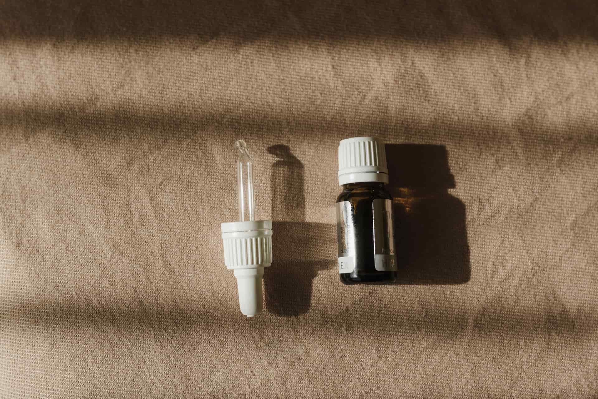 A glass serum dropper resting on a pale stone surface